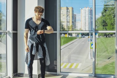 Büyük pencereler yanında duran ve saatler metro istasyonunda bakarak Genç adam.