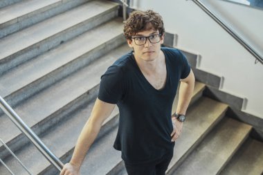 Siyah T-shirt metro istasyonu, merdivenlerden aşağı gidiş genç esmer adam.