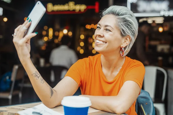 Attraktiva blonda flickan att göra selfie på café och dricka kaffe — Stockfoto