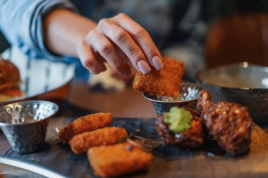 Kızarmış peynir tutarak ve bir sos daldırma kadın el yakın çekim.