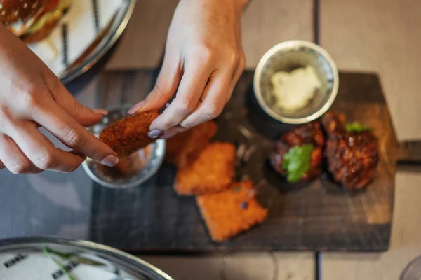 Close up of woman hands holding fried cheese and dipping it into a sauce. — Stock Photo, Image