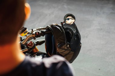 Motosiklet üzerinde oturan ve yan dikiz aynasında yansıtan yakışıklı motorcu, yakın çekim. Kentsel arka plan.