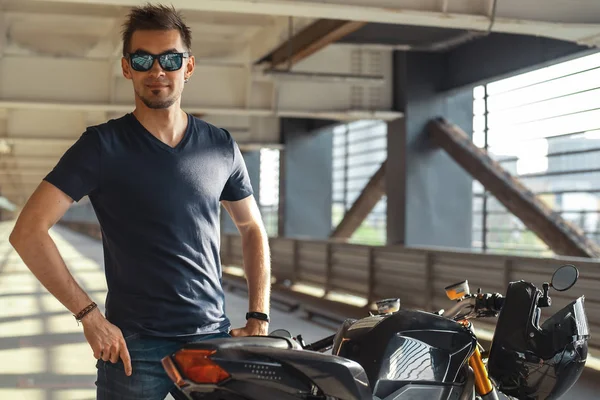 Retrato Motociclista Atraente Usando Óculos Sol Lado Moto Estacionamento Fundo — Fotografia de Stock