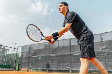 Tenis kortu tenis oynayan genç çekici adam uzak planı. Bir top ile Düzle strike hizmet için iki ele oyuncu holding kıyafeti.