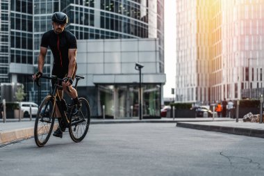Uzak plan atletik sporcu binme profesyonel bisiklet yanında modern binalar ve gökdelenler. Kentsel arka plan. Motorcu sektörlerine eğitim gün şehir, Tarih.