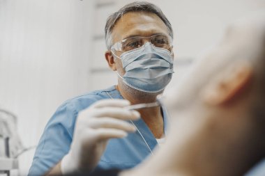 Bir dişçi istemci diş sağlık koşulu denetleme mavi üniformalı yakın çekim.