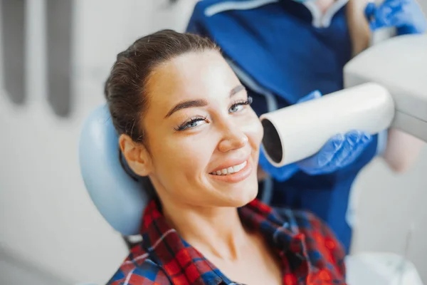 Κοντινό πλάνο του προγράμματος-πελάτη χαμογελώντας ενώ οδοντίατρος στο μπλε στολή κρατώντας ακτίνων χ. — Φωτογραφία Αρχείου
