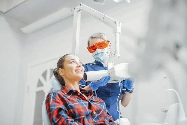 Client smiling while dentist in blue uniform holding x-ray. — Stock Photo, Image