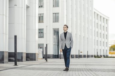Modern iş merkezi yanında gidiş genç iş adamı uzak planı.