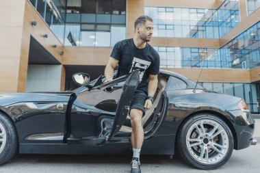 Genç çekici adam spor arabadan uzak planı. Yan görünüm.
