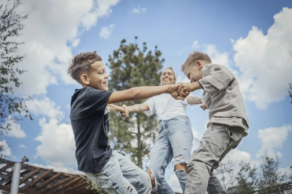 Joven mamá rubia dando la vuelta, girando con sus hijos en el parque . —  Fotos de Stock