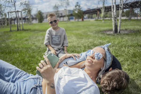 Primer plano de la madre y los hijos que yacen en el parque sobre hierba verde. Concepto de familia feliz . —  Fotos de Stock