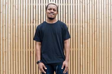 Genç çekici esmer adam ahşap arka plan üzerinde siyah boş T-shirt, yakın çekim.