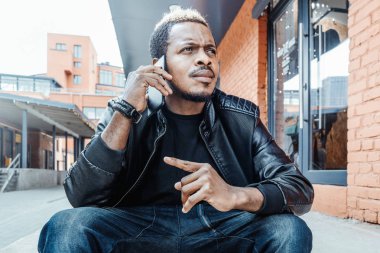 Cep telefonuyla konuşurken ve basamaklarında oturan esmer dalgın adam.