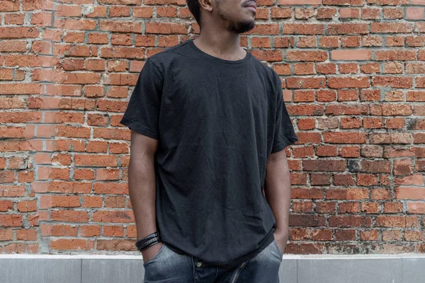 Esmer adamın tuğla zemin üzerine boş siyah T-shirt yakın çekim.