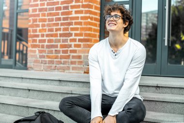 Modern bina ve Not defteri elinde tutan adımlar üzerinde oturan dalgın adam.