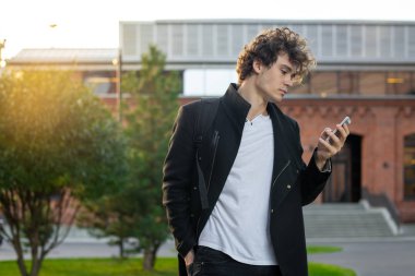 Siyah ceket cityscape kentsel arka plan cep telefonu ekranına bakarak adam.