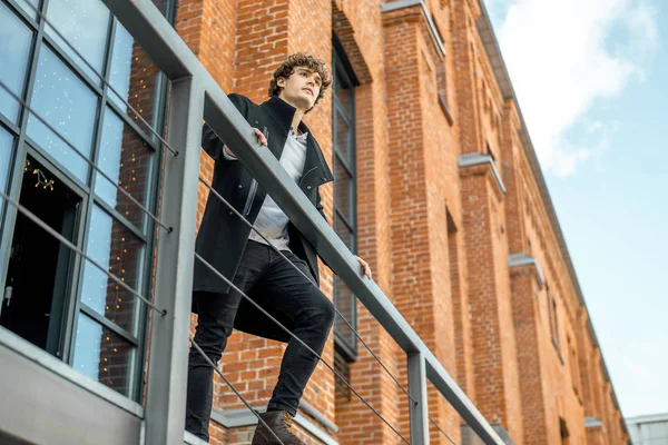 Çekici dalgın adam kırmızı tuğla bina arka plan üzerinde merdiven üzerinde ayakta.