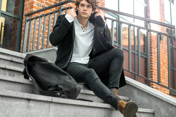 Somut adımlar üzerinde oturan ve siyah ceket bitiriyor dalgın adam