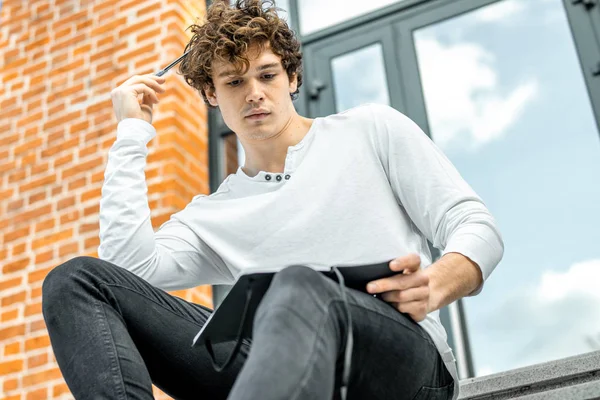 Not etmek onun elinde tutan ve somut adımlar üzerinde oturan çekici adam.