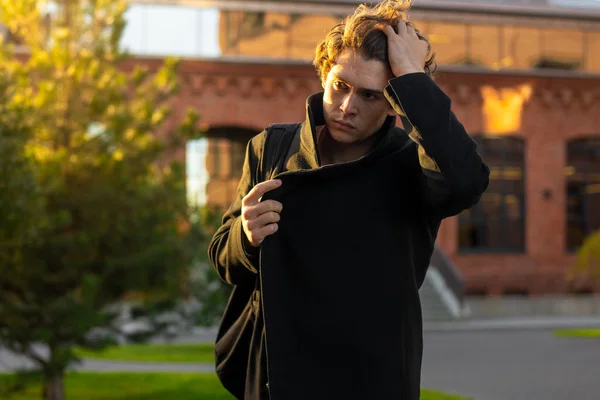 Close up of man in black coat touching his hair on cityscape background. — Stock Photo, Image