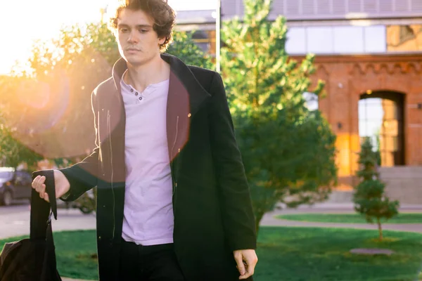 Kırmızı tuğla modern binalar geçen siyah paltolu adam yakın çekim.