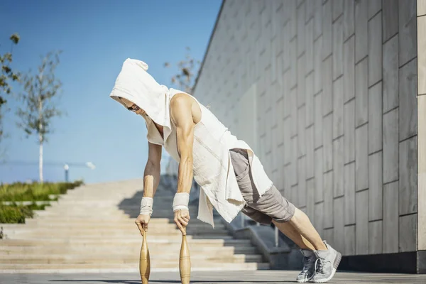 Homme athlétique attrayant pratiquant le yoga avec des messes à l'extérieur dans le parc moderne . — Photo