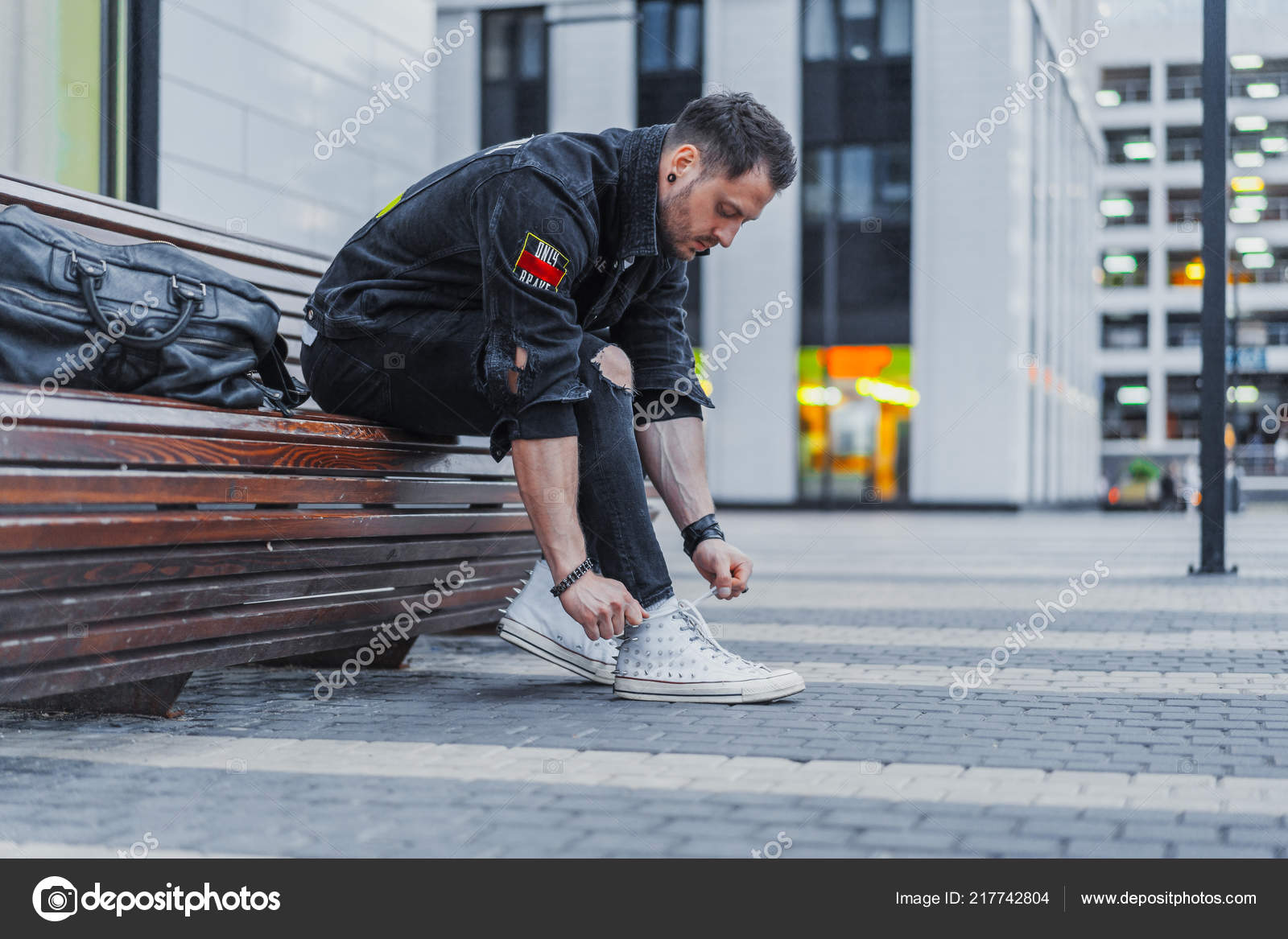 Attractive Man Tying Laces Of His Sneakers And Sitting On Bench At