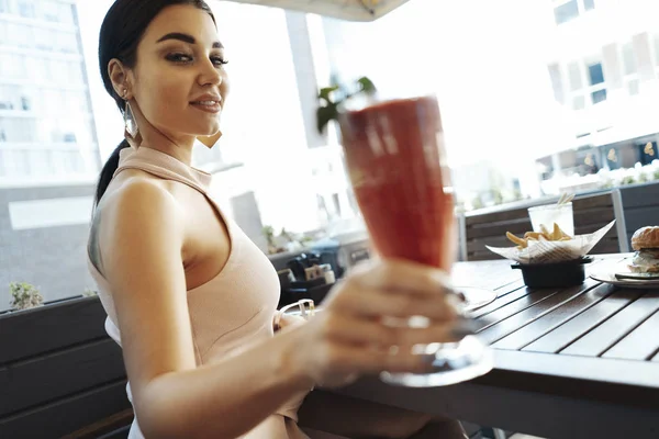 Крупный план молодой привлекательной женщины звон стаканов смузи в уличном кафе . — стоковое фото