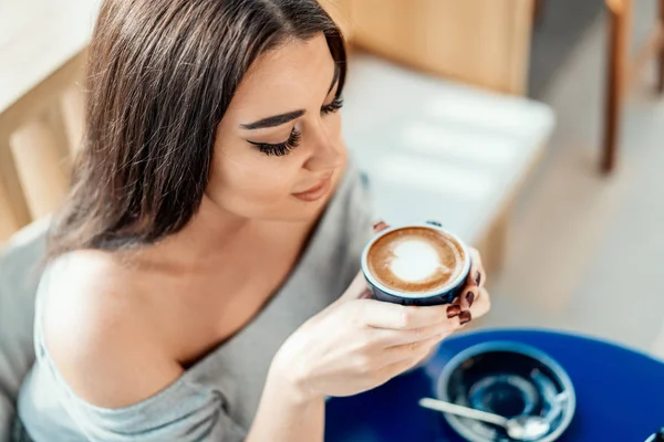 Primer plano de la joven hermosa mujer sosteniendo la taza de café y disfrutando de su aroma . — Foto de Stock