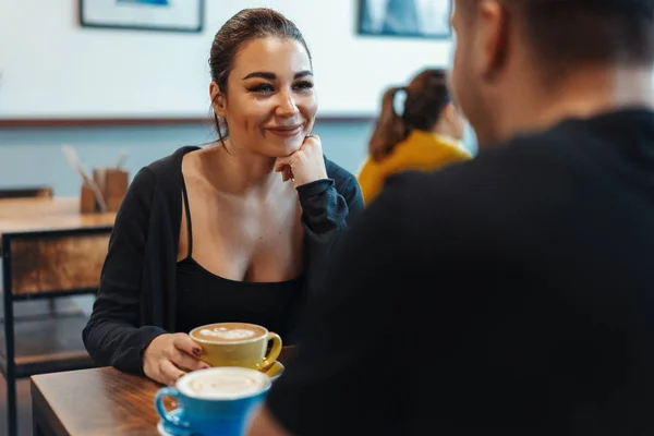 Pareja joven sentada en la cafetería en la cita, tomando café y comiendo postre . — Foto de Stock