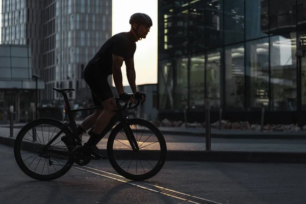 Sportsman montar en bicicleta profesional junto a edificios modernos y rascacielos . —  Fotos de Stock