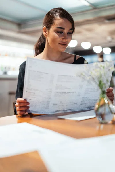 Mladá krásná žena při pohledu na nabídku rozhodnutí, co je na objednávku v moderní kavárně. — Stock fotografie