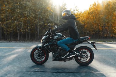 Güzel sonbahar ormandaki boş yolda motosiklet Binme sürücü.