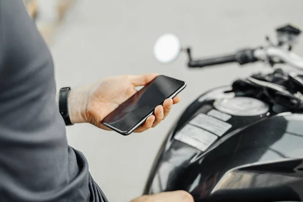 Motosiklet üzerinde otururken cep telefonu tutan motorcu, yakın çekim.