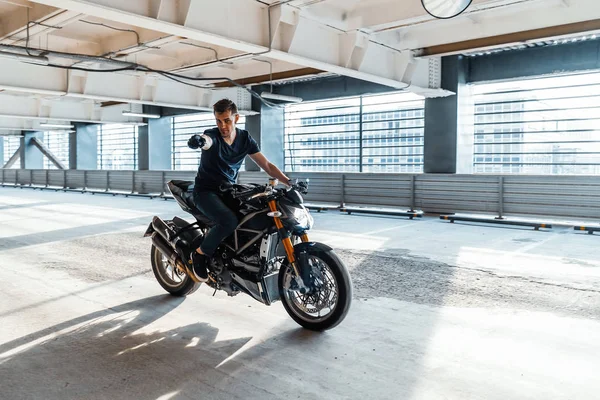 Plano de distância de motociclista andar de moto no estacionamento. Fundo urbano . — Fotografia de Stock