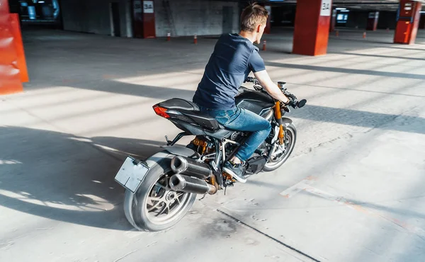 Plan distante de motociclista a caballo en el aparcamiento. Fondo urbano . —  Fotos de Stock