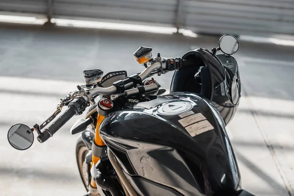 Primer plano del casco negro brillante en el manillar de la motocicleta. Fondo urbano . —  Fotos de Stock