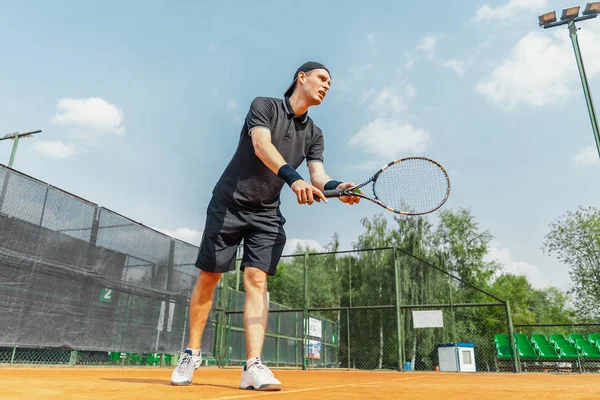 Plan lointain de l'homme jouant au tennis au court et battant la balle avec une raquette . — Photo