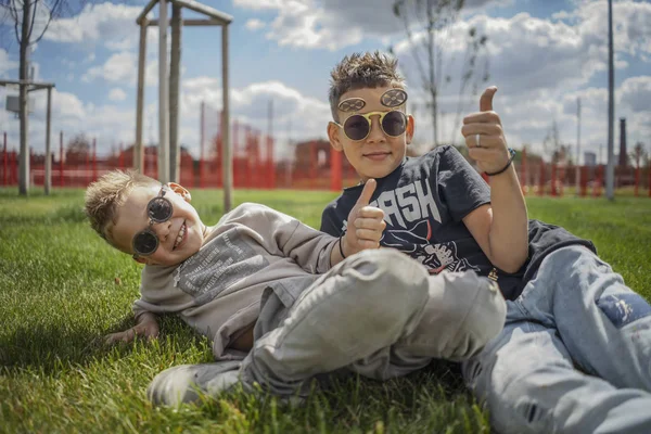 Zbliżenie chłopców siedzi w parku na zielonej trawie. Szczęśliwa rodzina koncepcja. — Zdjęcie stockowe