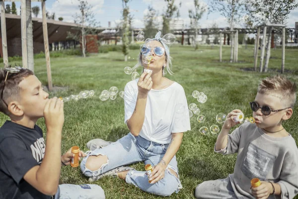 Happy family blowing bubbles outdoors in the park and having fun.