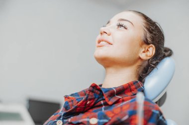 Bir stomatologist diş ofisinde beklerken gülümseyen istemcisinin yakın çekim.