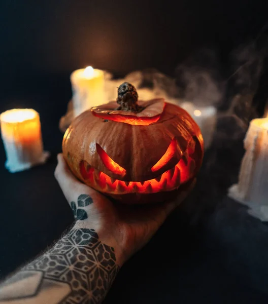 Man hand holding carved Halloween pumpkin on dark background. — Stock Photo, Image