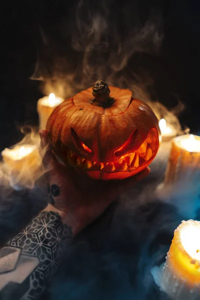 Homem mão segurando esculpida abóbora Halloween no fundo escuro . — Fotografia de Stock