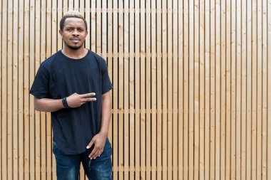 Ahşap arka plan üzerinde siyah T-shirt çekici esmer adamın yakın çekim.