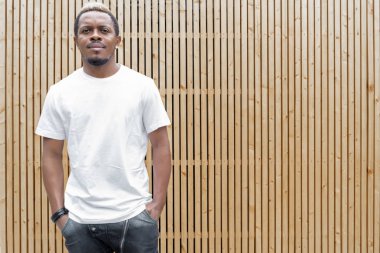 Ahşap arka plan üzerinde beyaz T-shirt çekici esmer adamın yakın çekim.