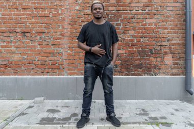 Genç çekici esmer adam kırmızı tuğla zemin üzerine siyah T-shirt.