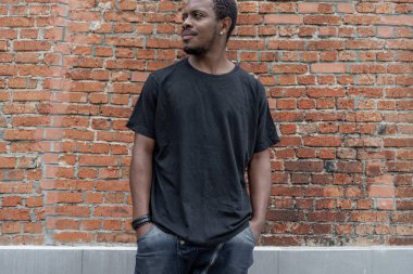 Genç çekici esmer adam kırmızı tuğla zemin üzerine siyah T-shirt.