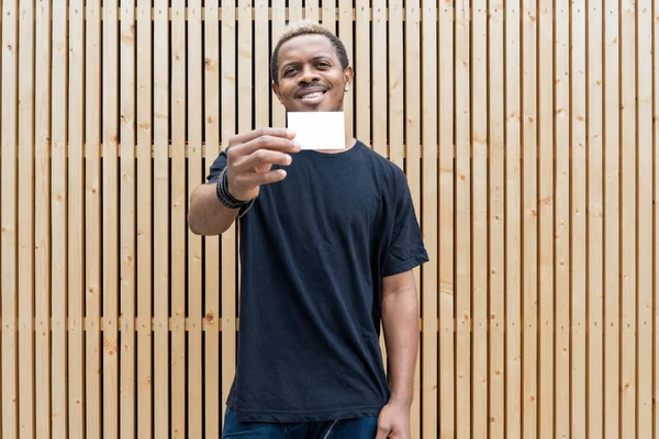 Hombre de piel oscura en camiseta negra mostrando la tarjeta de visita en blanco a la cámara . —  Fotos de Stock