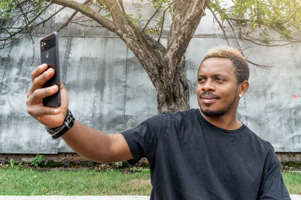 Primer plano del hombre de piel oscura en camiseta negra haciendo selfie en el teléfono móvil . — Foto de Stock